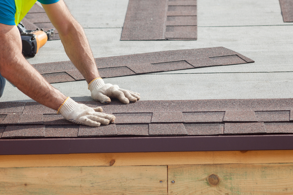 Roofer builder worker installing roof shingles